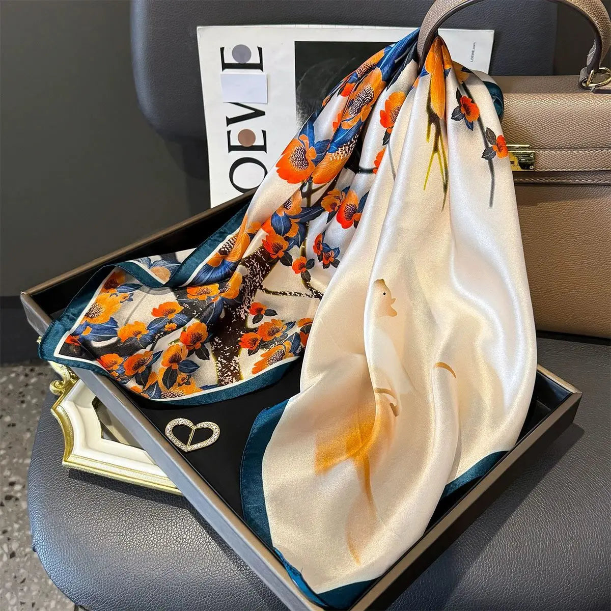 Carré en soie porté façon classique pour un style chic.FLEUR BLEU ORANGE