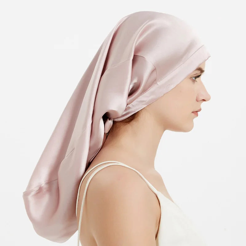 Femme portant bonnet de nuit en soie – cheveux bouclés protégés rose pale de coté